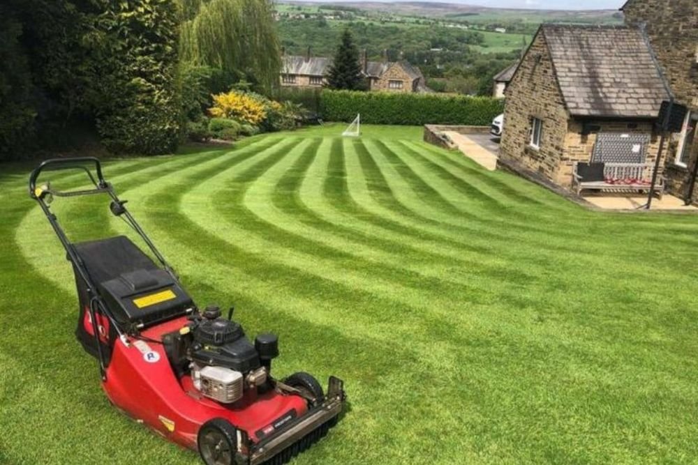 A lawn mower rests on a vibrant green lawn, showcasing a well-maintained outdoor space.